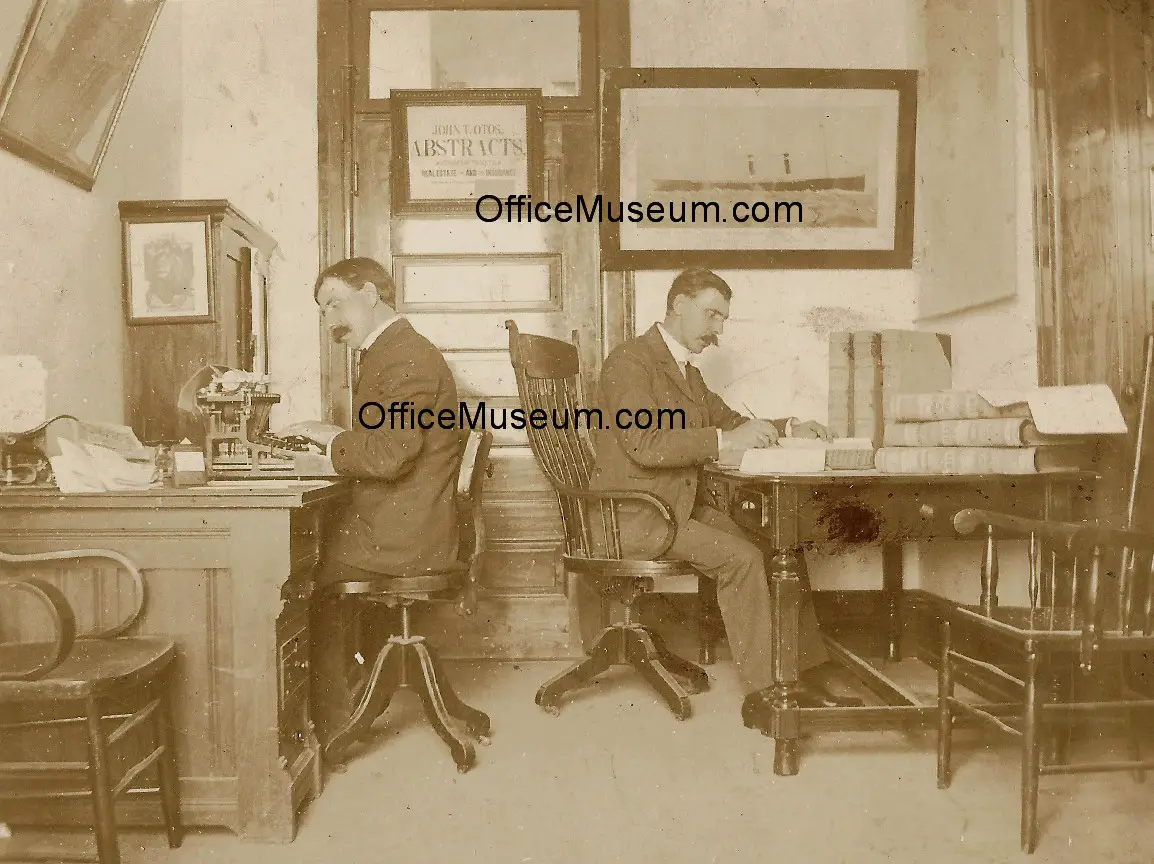 Two_men_in_office_with_upstrike_typewriter_plantation_desk_OM.jpg