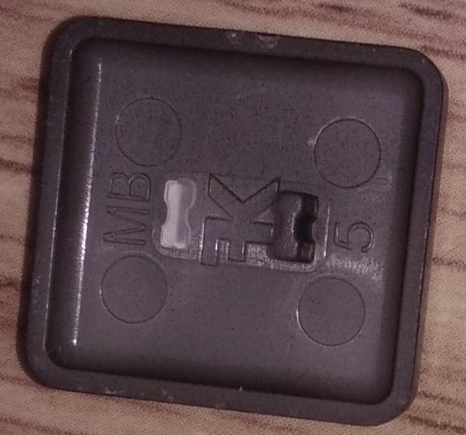 Right cursor keycap, backside: Broken mounting pin.
